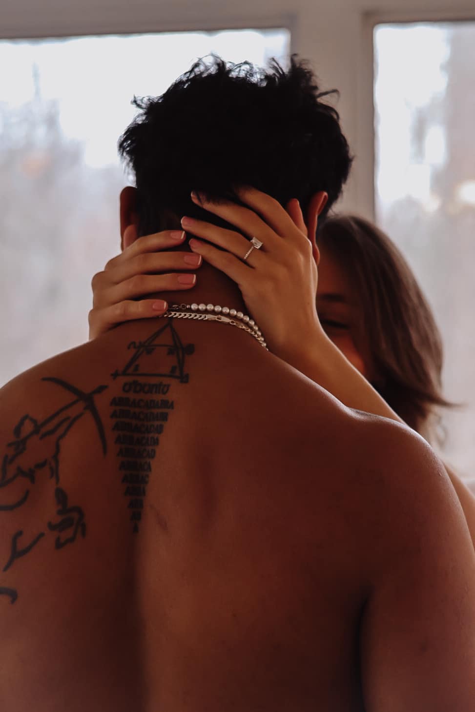 Engaged couple embracing with the ring on display, warm natural light